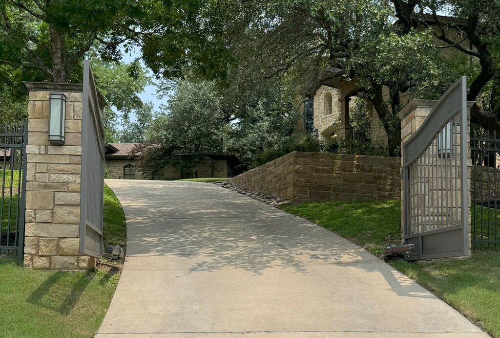 open gray automatic gate with stone facade posts