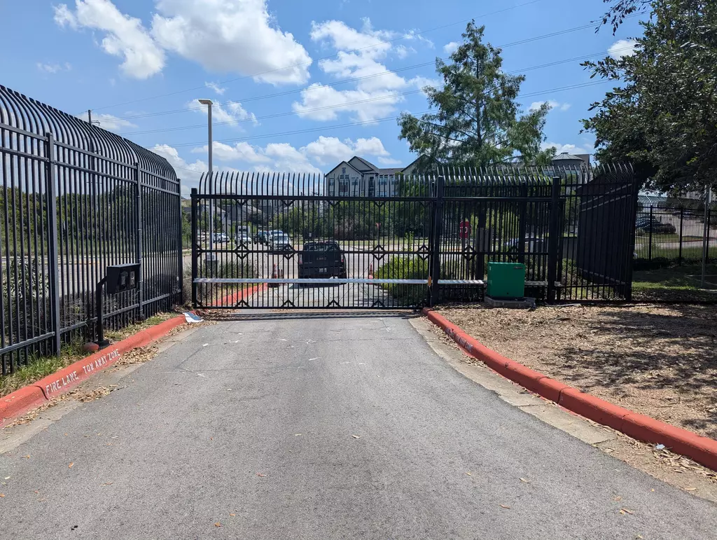 open gray automatic gate with stone facade posts