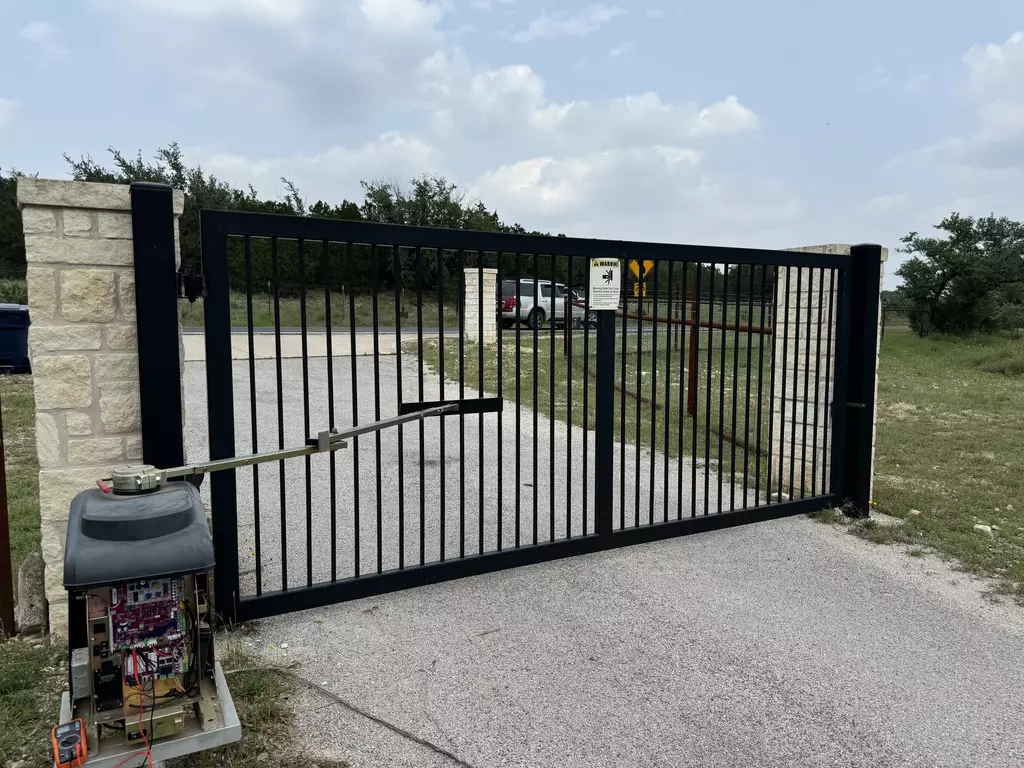 open gray automatic gate with stone facade posts