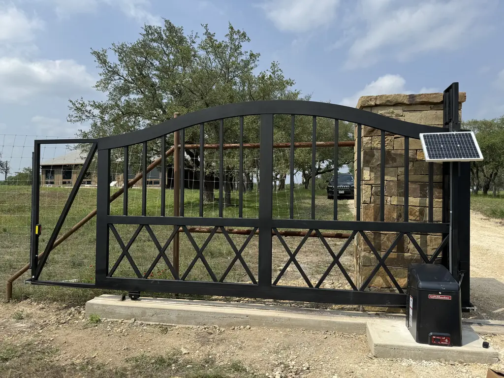 open gray automatic gate with stone facade posts