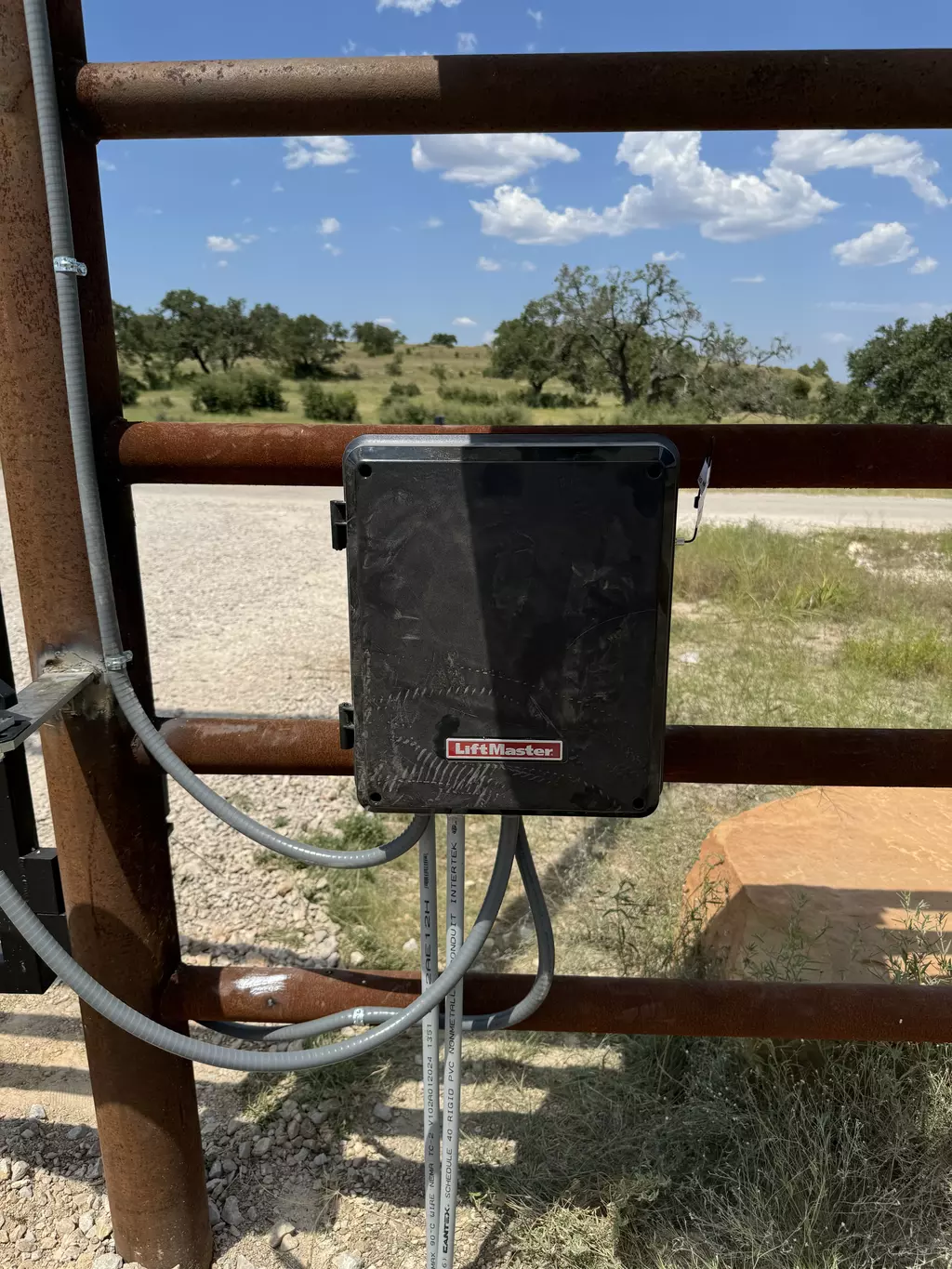 open gray automatic gate with stone facade posts