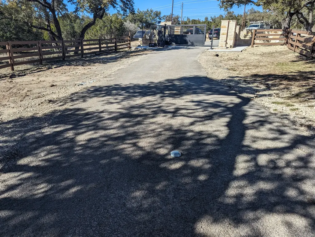 Gravel road with white ground sensor with black modern gate in background