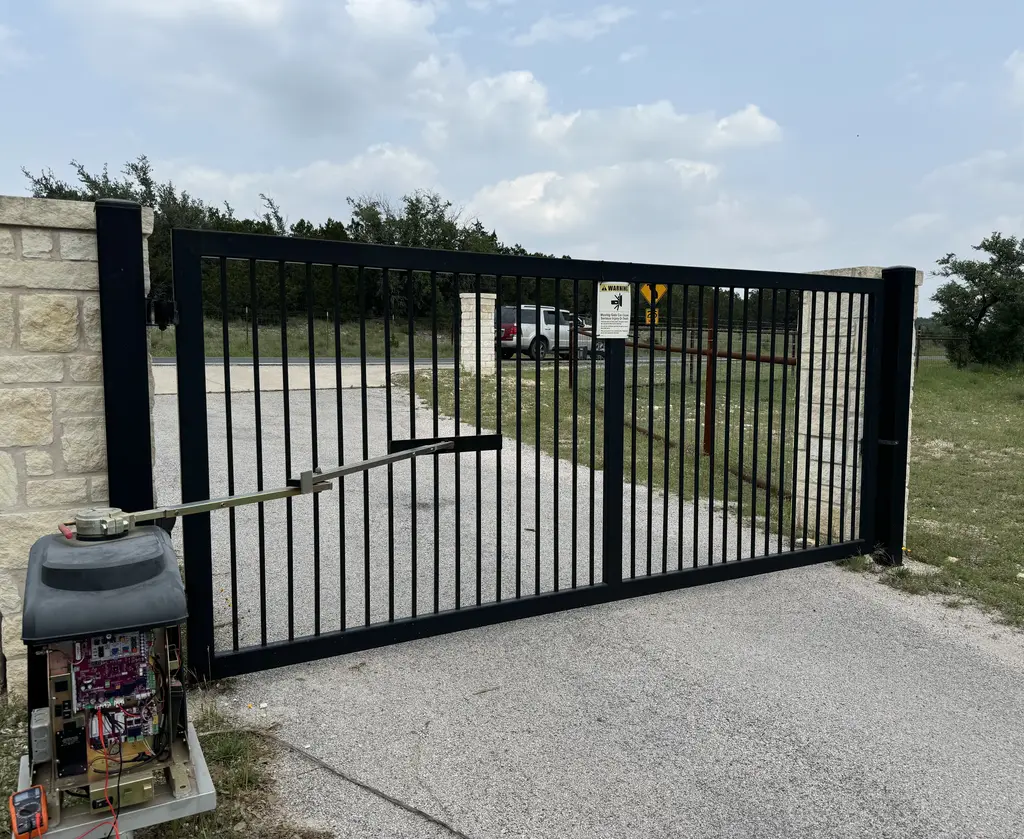 Articulated arm swing gate in black metal. Motor controlling the arm is in bottom left