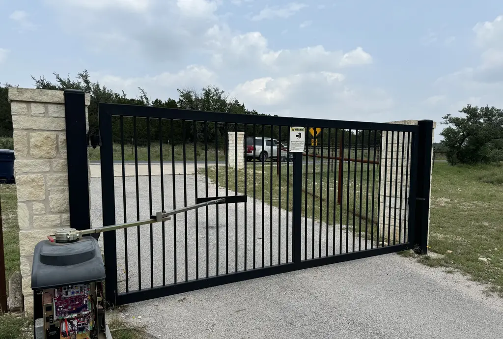 Articulated arm swing gate in black metal. Motor controlling the arm is in bottom left